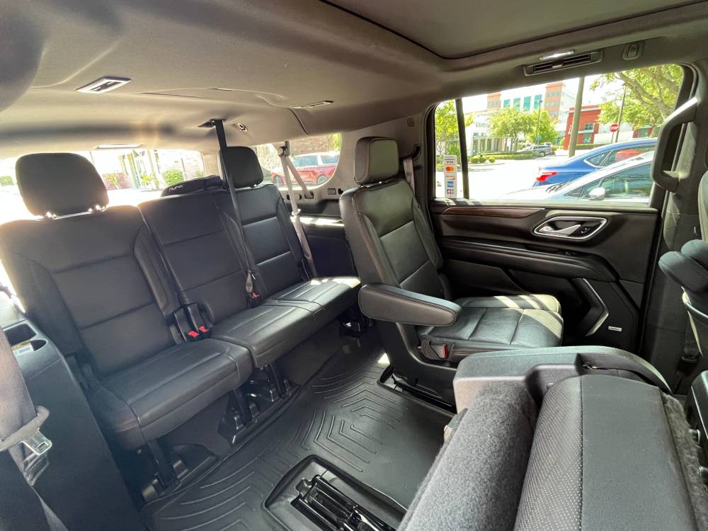 Interior view of a large SUV, perfect for Car Service Orange County, featuring three rows of black leather seats—captain’s chairs in the middle row and a bench seat in the rear.