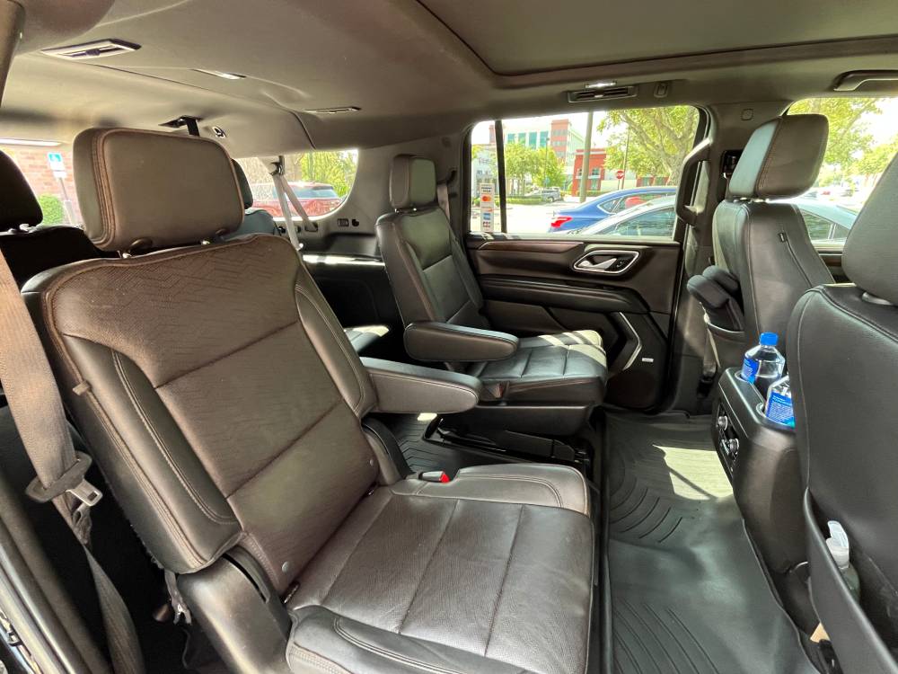 Interior view of an SUV used for Black Car Service Orlando, featuring two rows of black leather seats, captain’s chairs in the middle row, and a bottle of water placed on the rear console.