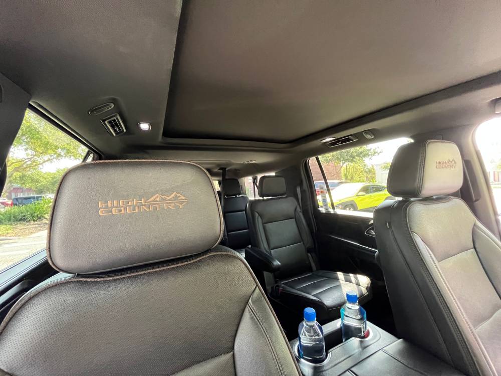 Interior of a vehicle with "High Country" embroidered on the leather seats, a sunroof above, and two water bottles in the center console cupholders—perfect comfort for your Car Service Orange County experience.