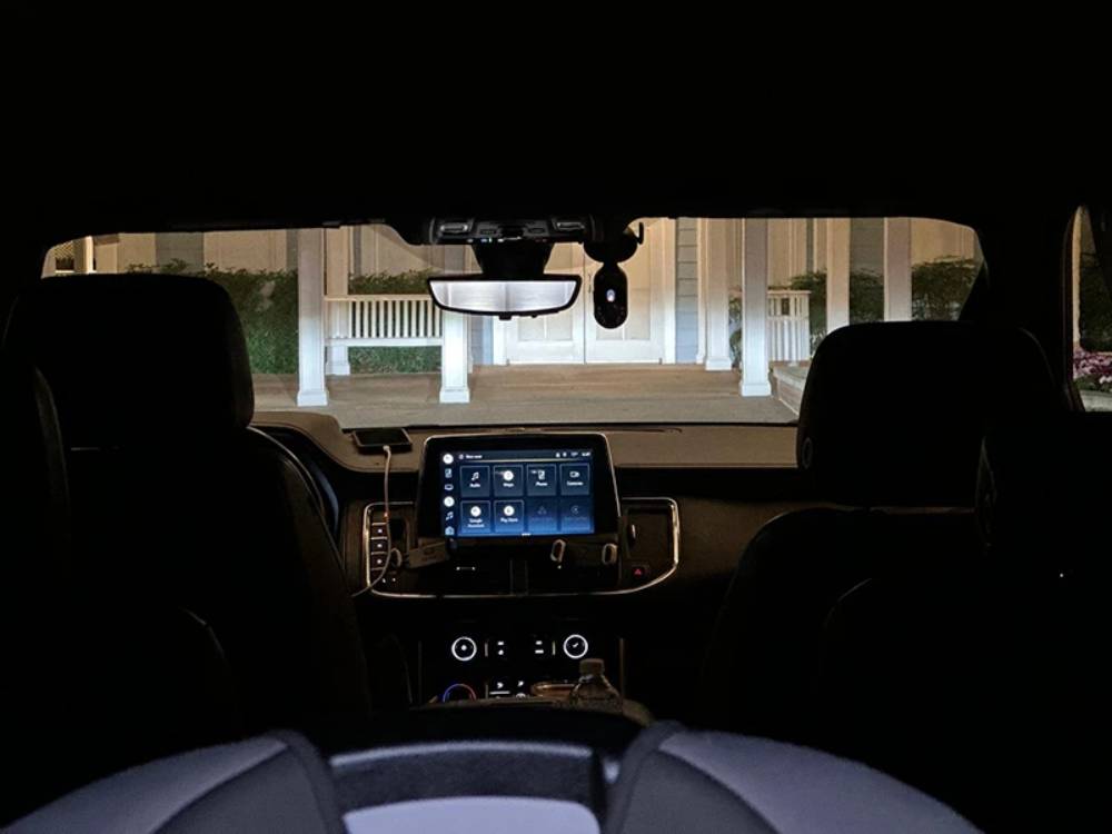 View from inside an Olive Luxury Ride at night, showcasing the sleek dashboard with digital display and a porch with white columns visible through the windshield.