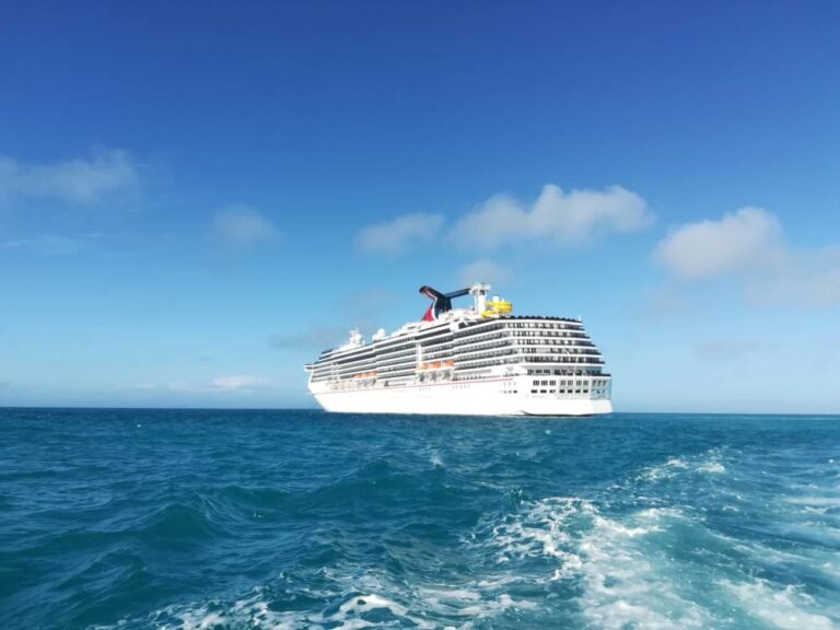 A large white cruise ship from Olive Luxury Ride sails on calm blue ocean water under a clear sky with a few clouds.